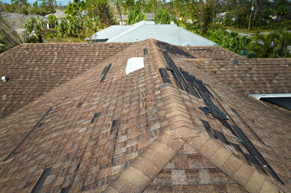 damaged-house-roof-with-missing-shingles-after-hurricane-ian-florida-consequences-natural-disaster 